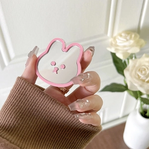 Close-up of pink rabbit-shaped phone grip with built-in makeup mirror and cartoon face