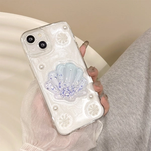 Gros plan d'une coque nacrée avec décor de coquillage 3D, paillettes et fleurs