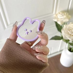Cute purple bunny phone grip with built-in mirror shown in hand against floral background