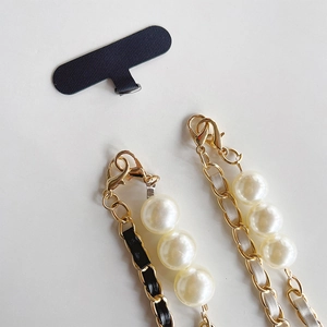 Detail of luxury gold metal phone straps with black and white leather and pearls
