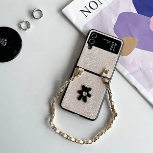 Detail of cream leather flip case featuring plush bear and gold chain crossbody strap