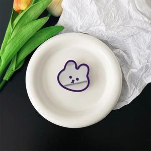 Macro shot of cute purple rabbit phone grip mirror on a white plate with floral decor