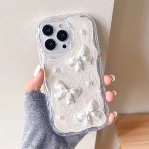 Détail d'une coque iPhone ondulée avec texture crème, nœud ruban et perles déco