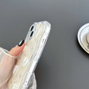 Dettaglio macro della cover in TPU con cuori 3D iridescenti e bordi antiurto rinforzati
