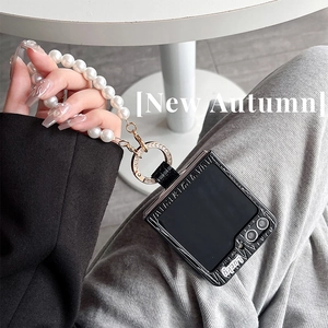 Detail of Galaxy Z Flip case with pearl hand strap and Lucky text in hand-held view