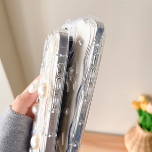 Détail de coque iPhone transparente ondulée avec perles 3D et décoration de nœud