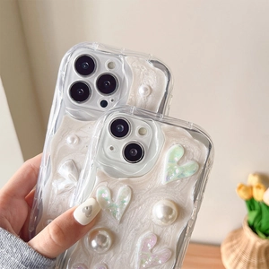 Détail de coque iPhone texture crème avec perles 3D, cœurs et nœuds papillon