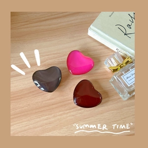 Minimalist heart-shaped resin phone socket grip in deep grey, pink, and dark red