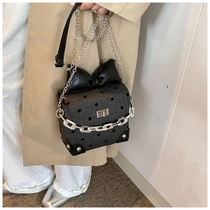 Detailed close-up of a mini crossbody bag with polka dots, oversized bow, and silver chains