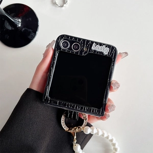 Detail of black crocodile texture phone case with pearl strap and Lucky metal tag