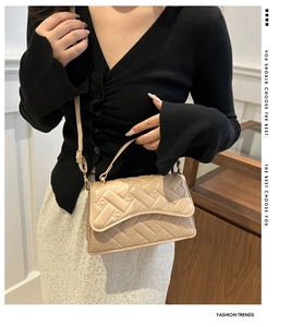 Close-up of geometric quilted beige shoulder bag with gold hardware and flap closure