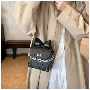 Polka dot mini crossbody bag featuring a large black bow and silver chain strap
