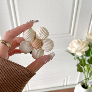 Gros plan d'un support de téléphone en fleur tricotée avec pétales beiges