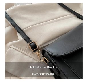 Detail of black leather shoulder bag showing golden adjustable buckle and precise stitching