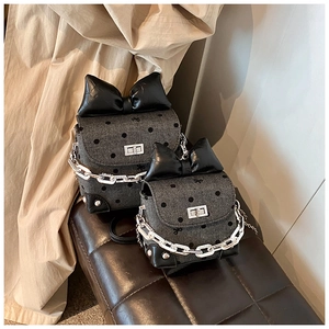 Detailed close-up of mini polka dot crossbody bag with leather bow and metal clasp