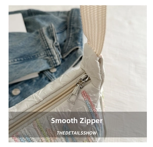 Detail of smooth metal zipper and colorful embroidery on white canvas dumpling bag