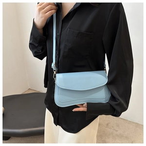 Detail of light blue PU leather square bag with curved flap and adjustable strap