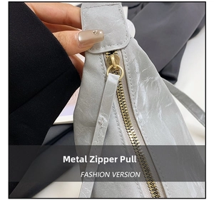 Detail of high-quality gold hardware zipper on a gray textured leather fashion bag