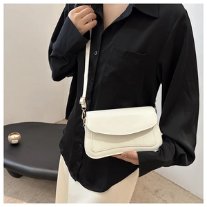 Close-up of minimalist white leather square shoulder bag with gold hardware detail