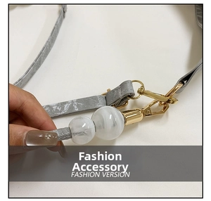 Detail of grey marble strap and golden metal hook on a modern women's shoulder tote bag