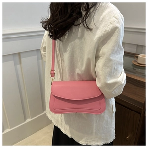 Detailed view of a pink rectangular shoulder bag with adjustable strap worn by a model