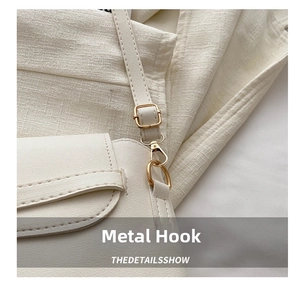 Close-up of golden hardware hooks and lychee grain leather on a beige crossbody bag
