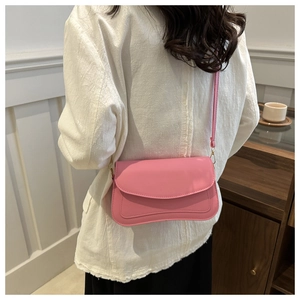 Rear view of a model wearing a pink PU leather shoulder bag with a curved flap design