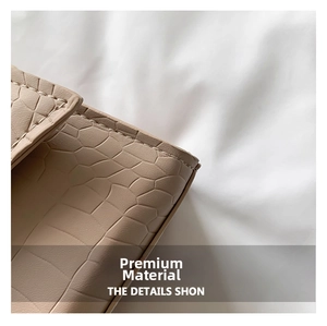 Macro detail of beige crocodile embossed leather with premium stitching on small square bag