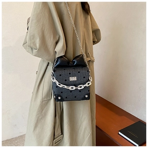 Detail of mini crossbody bag with polka dots, bow accent, and silver chain strap