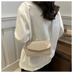 Detail of cream white crossbody bag featuring a unique wavy bottom edge design on leather