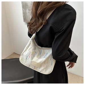 Detail of white nylon dumpling bag featuring colorful striped embroidery and logo label