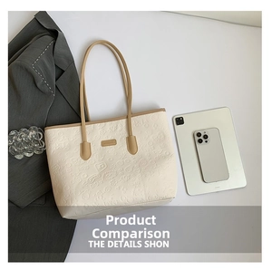 Flat lay of large beige leather tote bag with embossed cartoon motifs and khaki trim