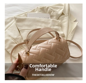 Close-up of beige quilted crossbody bag featuring heart embroidery and metal hardware