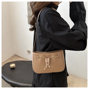 Detail shot of khaki leather shoulder bag with drawstring and golden ring on model