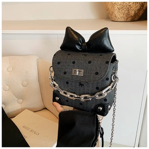 Detailed view of grey herringbone crossbody bag with polka dots and large bow detail