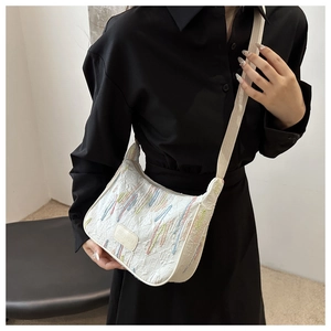 Detail of white dumpling bag with colorful embroidery and wide nylon shoulder strap