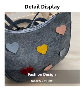 Detailed macro of grey crescent bag featuring colorful stitched leather heart patches