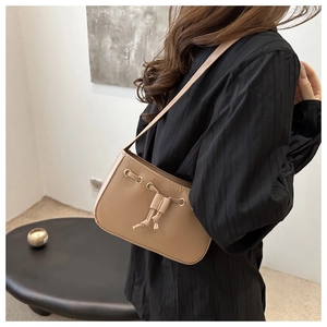Close-up of khaki leather shoulder bag featuring a decorative drawstring bow and gold eyelets