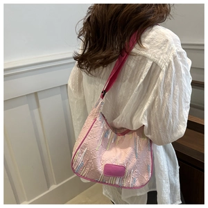 Detail of pink nylon dumpling bag featuring colorful embroidery and logo patch on model
