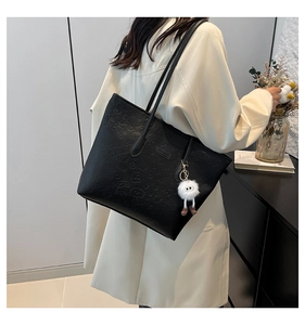 Detail of black embossed large tote bag with cute floral patterns and plush pendant
