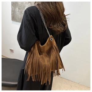 Détail du sac à franges en daim caramel avec bandoulière chaîne porté par un modèle