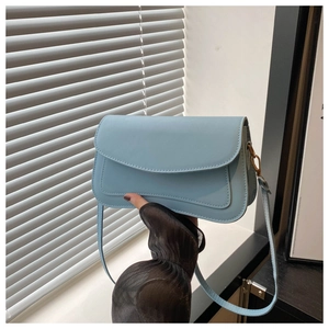 Detail of light blue crossbody bag with gold hardware and lychee grain leather texture
