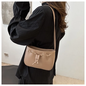Detail view of khaki mini shoulder bag with gold metal eyelets and drawstring knots