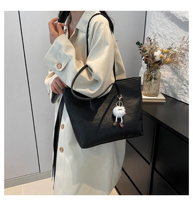 Chic black PU tote bag with unique monster embossing and plush charm accessory