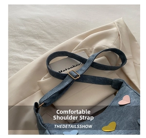 Detail of adjustable denim shoulder strap with colorful heart patches on a blue bag