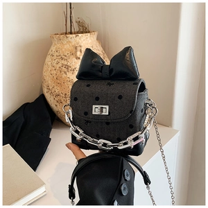 Detail of herringbone fabric crossbody bag with black polka dots and oversized bow