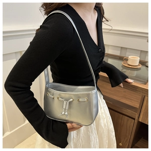Detail of silver metallic shoulder bag showing gold metal eyelets and drawstring closure