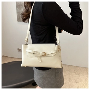 Close-up of cream shoulder bag featuring elegant gold buckle and smooth leather texture