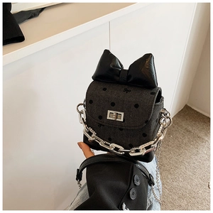 Detailed view of mini crossbody bag with polka dot pattern and large glossy black bow