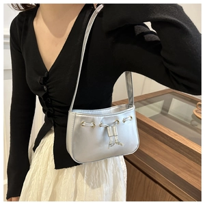 Detail of silver metallic shoulder bag showing drawstring design and metal eyelets